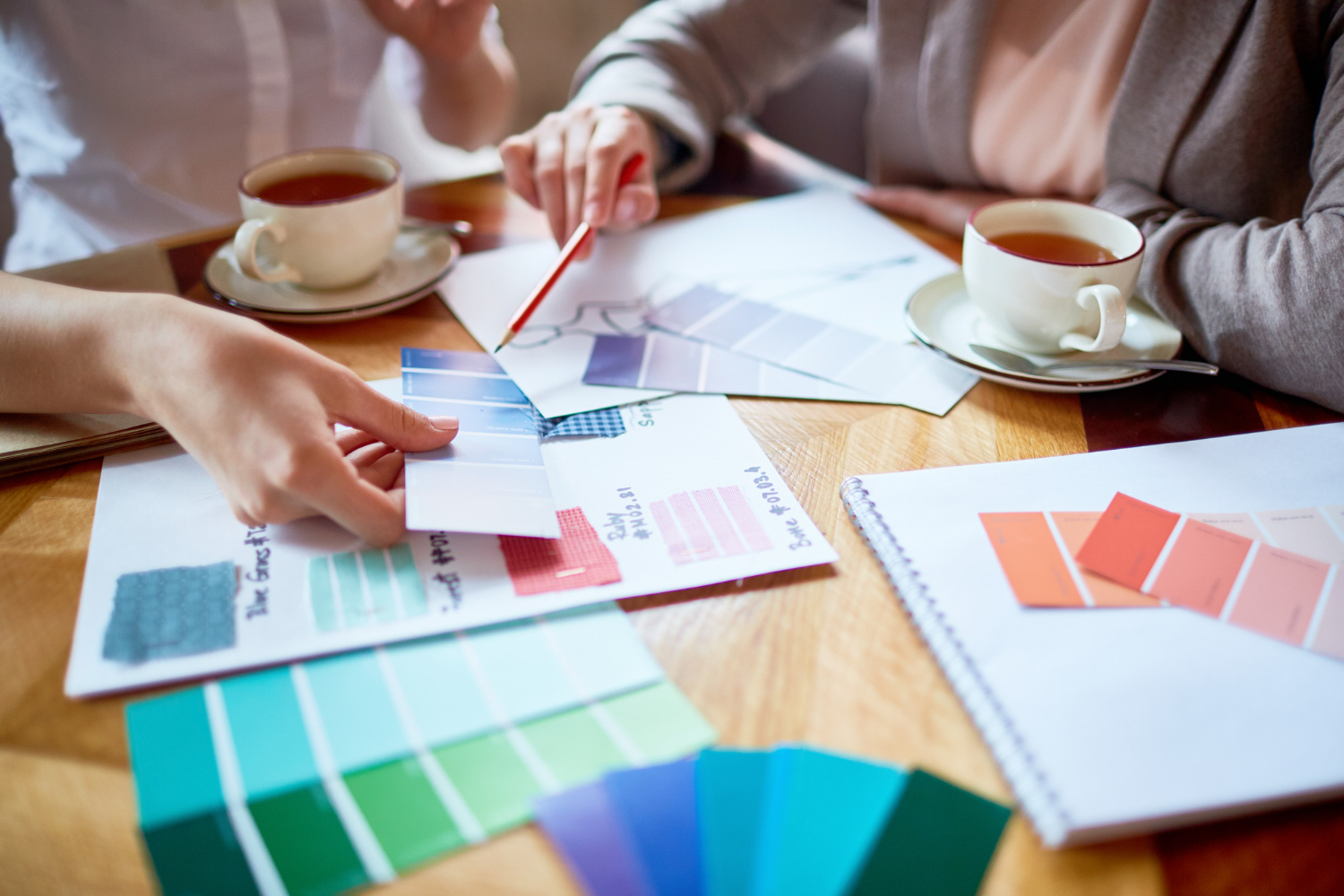 Manos revisando muestras de color sobre una mesa para elegir la paleta de una marca